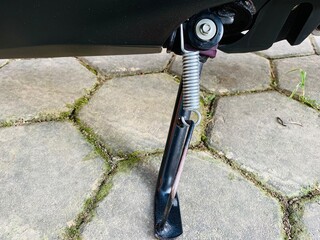 Close up motorcycle standard. Black iron standard at the motorcycle to support the motorbike when parking