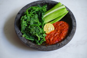 fresh vegetables and sambal in stone plate 