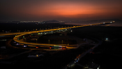 India's longest sea bridge: Trans-Harbour Sea Link. Atal Setu sea bridge in Mumbai, Maharashtra, India. Time-lapse of a city at night with bright skyscrapers and a dense network of glowing buildings.