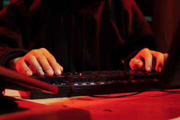 A man in a dark hoodie uses a laptop at night, symbolizing cybercrime, hacking, identity theft, and digital security threats.