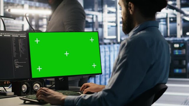 Data center technician doing software updates using green screen mockup computer. Server room IT specialist , optimizing infrastructure using chroma key isolated screen PC, camera A