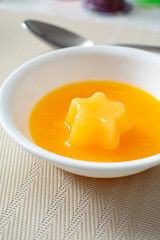 A view of a mango flavored fruit jelly cup, in a bowl.