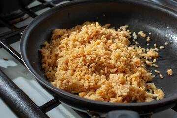 A view of Mexican rice cooking in a non-stick pan, on the stove.