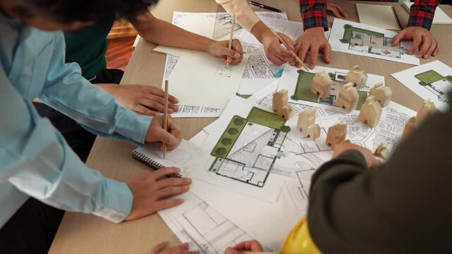 Architect and safety engineer discussion about building construction use blueprint on table with architectural document, measurement tool and wooden block scatter around at modern office. Delineation.