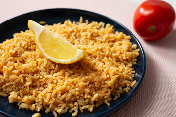 A view of a plate of Mexican rice, topped with a lemon wedge.