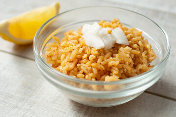 A closeup view of a small bowl of Mexican rice, topped with chopped onion.