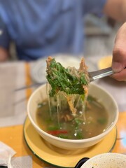 Authentic Thai jungle curry (Gaeng Pa) with fish or meat, herbs, and vegetables, a flavorful and spicy clear soup known for its intense aroma and bold taste. Features vermicelli noodles being lifted 
