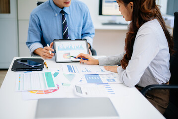 Obraz premium Two professionals reviewing business charts and data with tablet and documents. Ideal for financial planning, corporate teamwork, and modern office