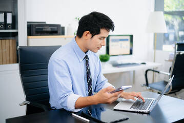 Fototapeta premium young professional man using smartphone at desk with laptop and tablet. Perfect for business, technology, remote work