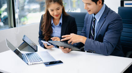 Asian business team in suits discussing ideas at desk with laptop. Great for themes of teamwork, leadership, productivity, planning,