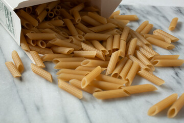 A view of a pile of gluten-free penne spilling out of the box.