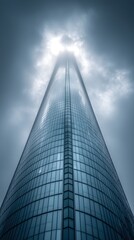 Naklejka premium Tall, glass skyscraper ascends into clouds