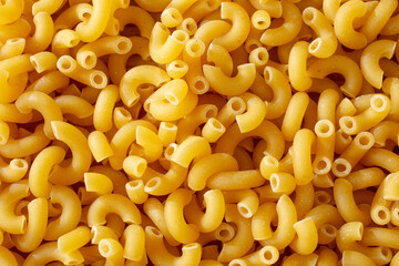 A top down view of a layer of dry small elbow macaroni, as a background.