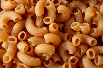 A top down view of a pile of dry cassava elbow pasta, as a background.
