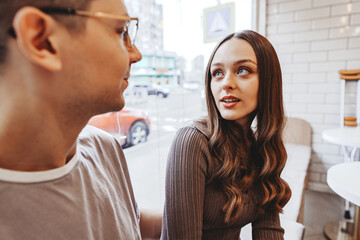 Engaging conversation between two young adults in a cafe during a sunny afternoon in a city