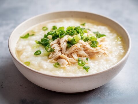 Bowl of chicken congee with shredded chicken and green onions, comforting Asian dish