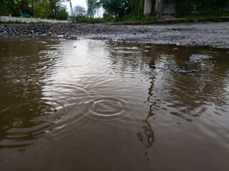 A puddle of water with drops of rain on a cloud day