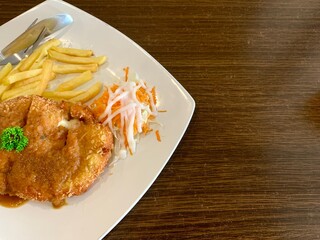 Chicken cordon bleu on the white plate, with french fries and salad. Delicious food
