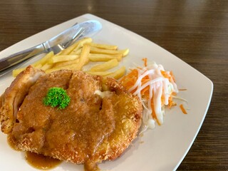 Chicken cordon bleu on the white plate, with french fries and salad. Delicious food