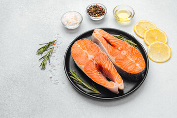 Fresh salmon fillets prepared with lemon and herbs on a dark plate