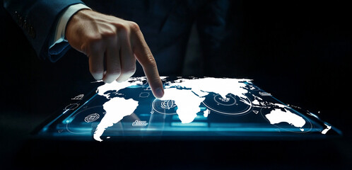 Handsome businessman interacting with a holographic world map display in a dark environment showcasing technology and connectivity concepts seamlessly