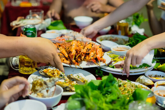 Gathering of friends enjoying a seafood feast at a vibrant outdoor setting during a warm evening