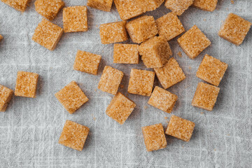 Brown sugar cubes scattered on a linen cloth in a bright kitchen setting
