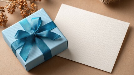 Blue gift box with bow and graduation cap sticker next to blank white paper, beige background, top-down HD close-up, modern minimalist style for graduation social media and packaging design