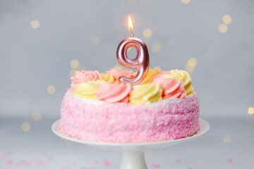 Celebration with a pink and yellow cake featuring a number nine candle