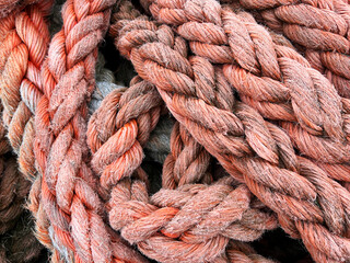 Close-up of rough braided marine ropes with visible fibers and aged surface, forming tight knots and loops