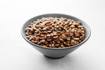 Side view of full bowl with dry dog food kibbles on white background