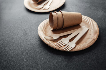 Biodegradable paperware set with wooden forks on black background