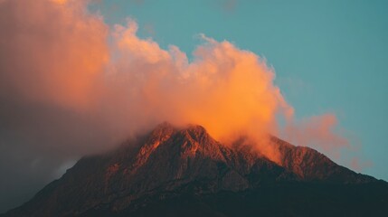 Fototapeta premium Photo of a mountain peak with orange light in the clouds at sunset. Minimal nature landscape background.