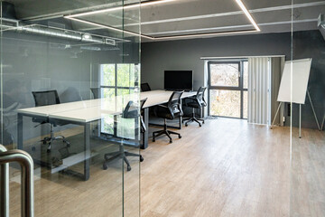 Modern conference room with glass walls and large windows showcasing a serene outdoor view during daytime
