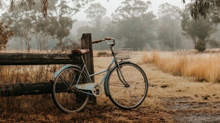 Fototapeta premium Vintage Bicycle by Rustic Fence in Foggy Countryside Landscape