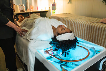 In a modern salon, a beautician prepares a client for a hair treatment involving pressurized water,...