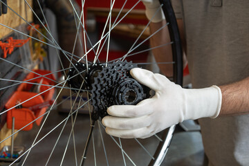 Mechanic in white gloves holding bicycle wheel