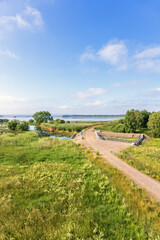Dirt road over a dam by a lake in a beautiful summer landscape