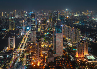 Obraz premium Night aerial view of skyscrapers and multi lane highway in large urban city center Cityscape of high rise buildings in Jakarta, Indonesia at night
