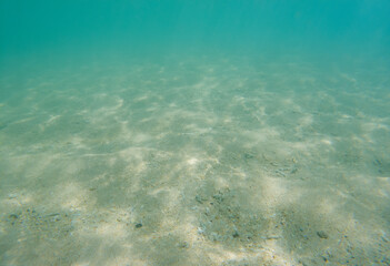 A clear blue ocean with a sandy bottom