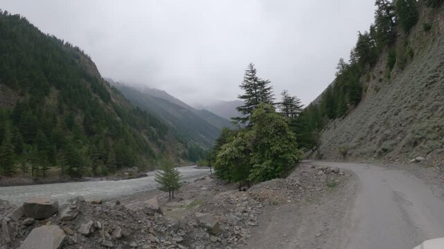 4k POV shot of a vehicle drive besides the river Chenab during a cloudy day as seen on the way to Udaipur in Pattan Valley, Lahaul, Himachal Pradesh, India. Scenic drive besides the river in Himalayas
