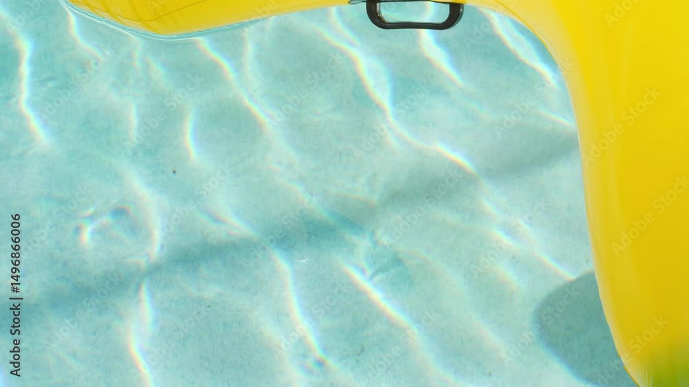 Poster Beautiful ripples dance on the floor of a sunny pool while a yellow pool floaty moves around the edge of the frame in slow motion.
