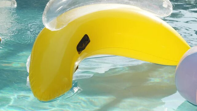 A banana shaped floaty moves through the sunny water in slow motion