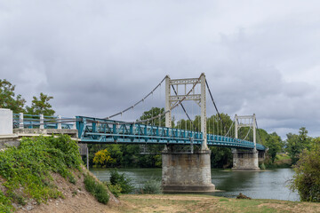 Suspension bridge crossing Garonne River in Auvillar, France, under cloudy sky