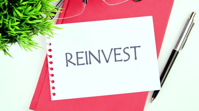 REINVEST the word appears on the leaf of the notebook. REINVEST text animation. Business and reinvest concept.