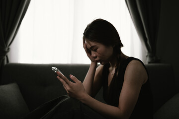 A young woman sits alone indoors in dim light, overwhelmed by sadness, anxiety, and emotional...