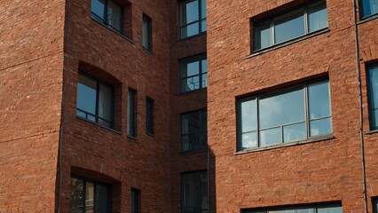 Obraz premium Modern brick residential building close-up. Perspective view of a house wall with windows and balconies.