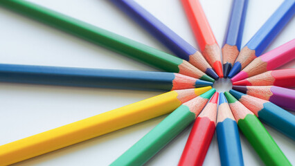 Close-up of colored pencils arranged in a radial pattern. The vibrant hues fan out from a central...