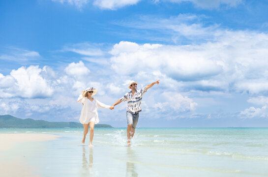 Couple holding hands running on the beach with vacation or holiday and happy for bonding, smiling and sea with honeymoon, fun and free.