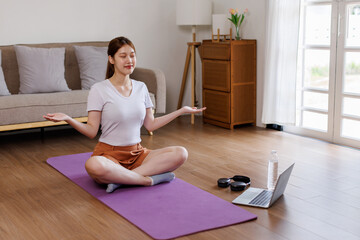 asian woman, yoga and video with laptop on floor in home, health and breathing exercise for online course in morning. woman happy with computer, pilates or ready for virtual class at apartment
